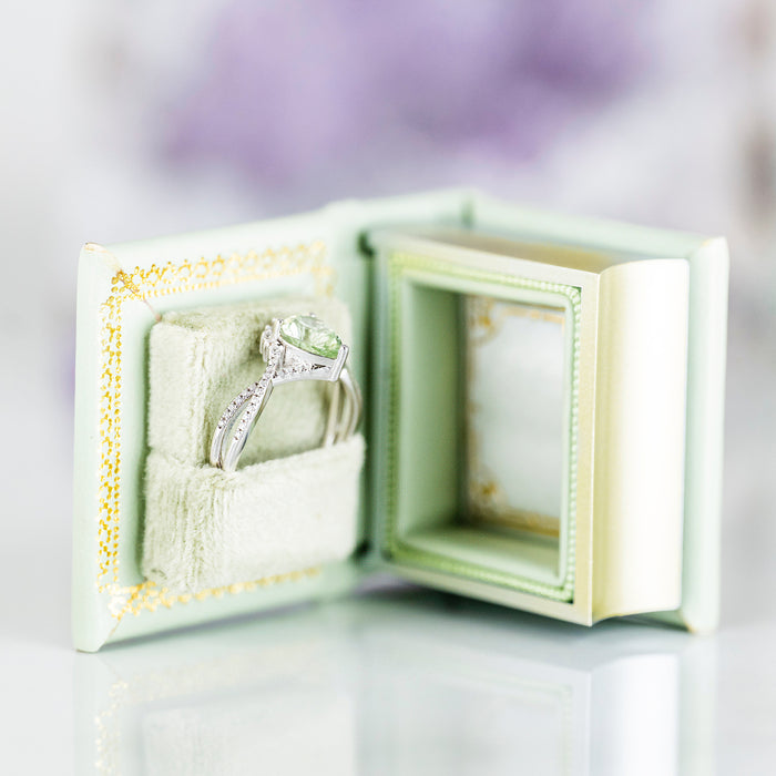 Spring Court Handmade Leather Book Ring Box- Bloomlight Green Edition (Small) by Aquamarise, open soft green box holding a silver ring with a green gemstone inside.