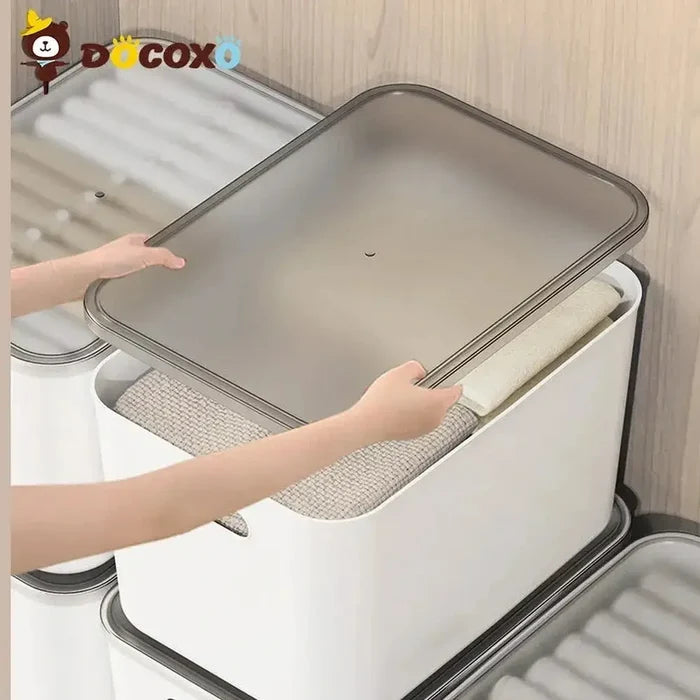Person opening stackable storage bins with clear lids to reveal stored items.