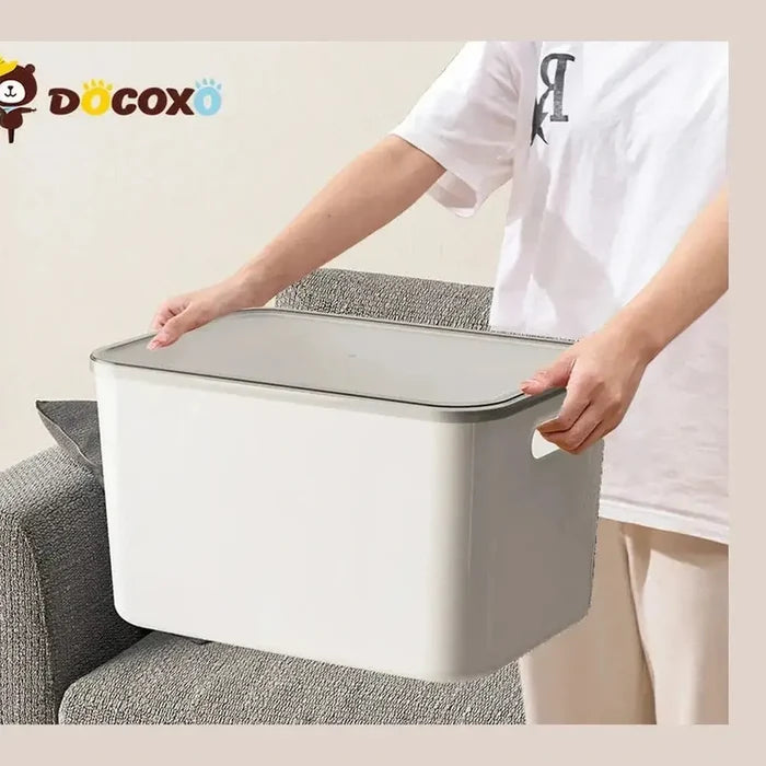 A person holding stackable storage bins with clear lids to organize clutter, demonstrating convenience and practicality.