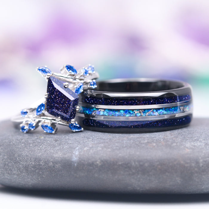 Starry Night and Fire Opal Leaf Couples Ring Set by Aquamarise, featuring a dark celestial-inspired band inlaid with shimmering blue opal and a silver ring with a square galaxy sandstone centerpiece accented by delicate blue leaf gemstones, part of Matching Couples' Rings and Starry Night™ Collections.