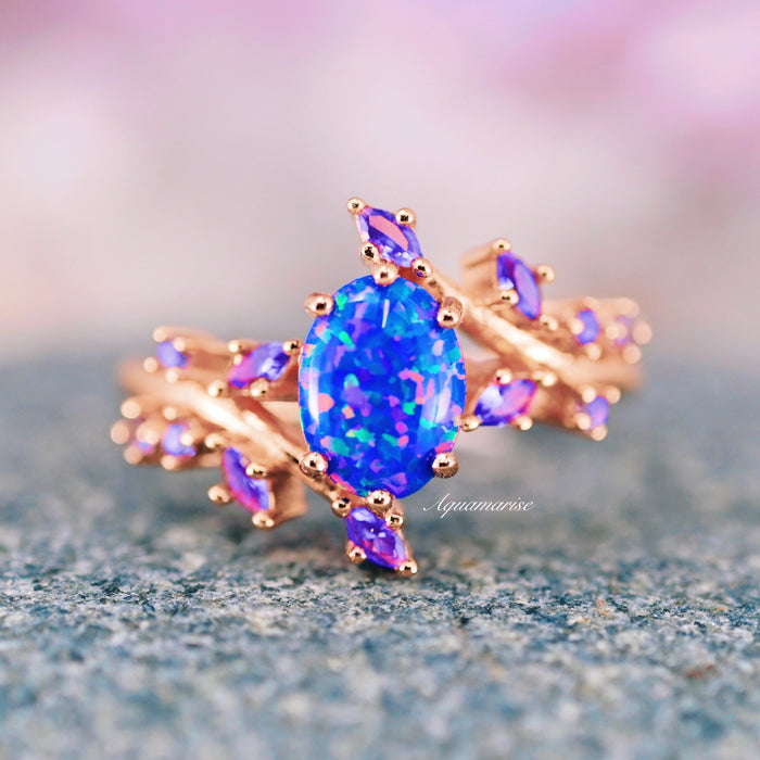 Starry Night Van Gogh Fire Opal & Rose Gold Leaf Couples Ring Set by Aquamarise, featuring an oval fire opal centerpiece with vibrant blue and purple hues, accented by marquise-shaped purple gemstones on a rose gold band.