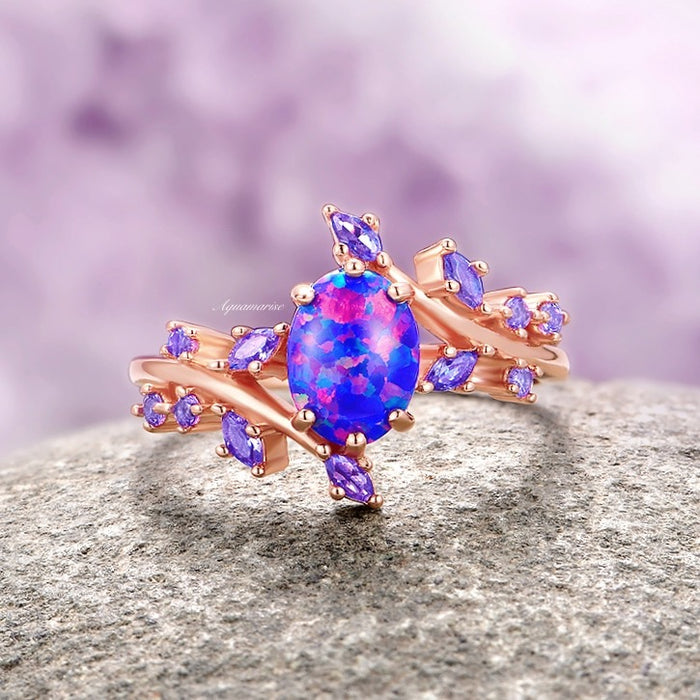 Starry Night Van Gogh Fire Opal & Rose Gold Leaf Couples Ring Set by Aquamarise, showcasing an oval fire opal centerpiece with vibrant pink and blue hues, accented by marquise and round violet gemstones on a rose gold band inspired by delicate leaves.