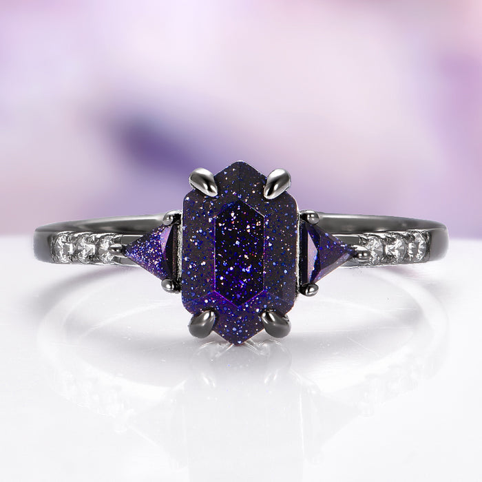 Ring with purple gemstone and diamond accents on a white surface with a blurred purple background