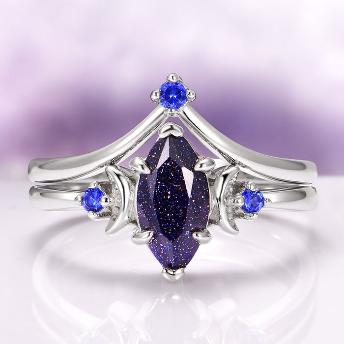 Lunar Starlight Sandstone Ring Set (Starry Night) in 14K White Gold featuring a marquise-cut blue sandstone with sparkling gold flecks, accented by vibrant blue gemstones on elegant white gold bands by Aquamarise Gold.