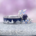 Starry Night & Trees Couples Ring Set by Aquamarise, featuring a polished silver band with deep blue galaxy sandstone and tree silhouette, paired with a delicate silver ring accented by sparkling blue and clear gemstones.