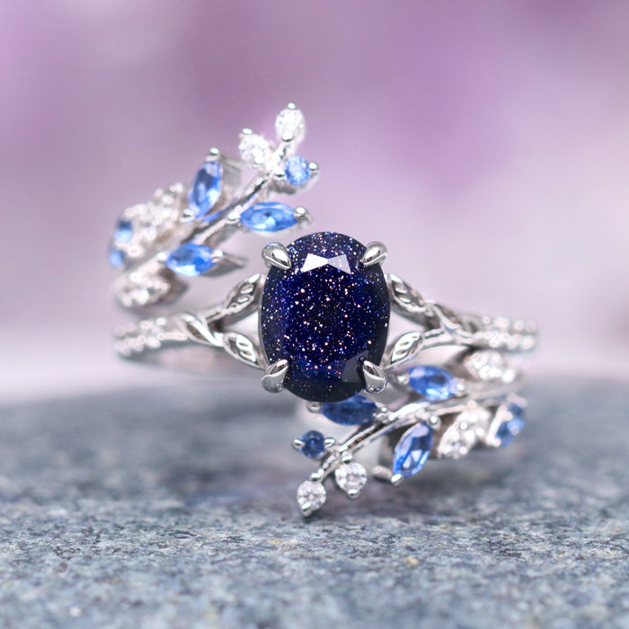 Starry Night & Sapphire Leaf Ring Set- 14K White Gold featuring a deep blue sapphire center stone surrounded by delicate leaf motifs with small blue and white gemstones, crafted by Aquamarise Gold from nature-inspired and starry night collections.