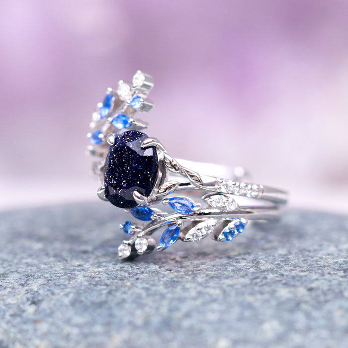 Starry Night & Sapphire Leaf Ring Set- 14K White Gold featuring a deep blue sandstone center stone with intricate leaf-inspired sapphire and diamond accents on delicate white gold bands, crafted by Aquamarise Gold.