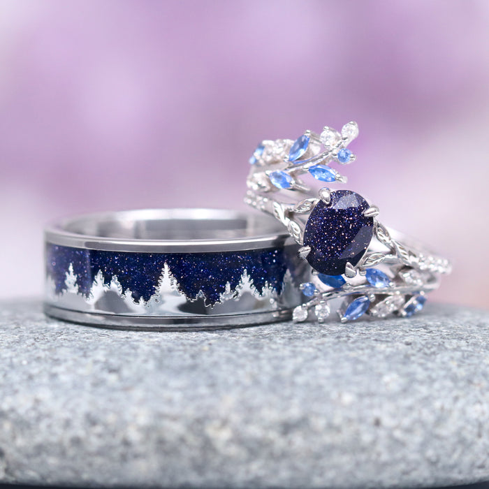 Starry Night & Trees Couples Ring Set by Aquamarise, featuring a polished silver band with deep blue galaxy sandstone and tree silhouette, paired with a delicate silver ring accented by sparkling blue and clear gemstones.