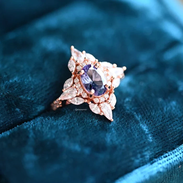 Stella Alexandrite Ring- 14K Rose Gold Vermeil by Aquamarise, featuring an oval color-changing alexandrite surrounded by marquise and round stones on a luxe blue velvet background.