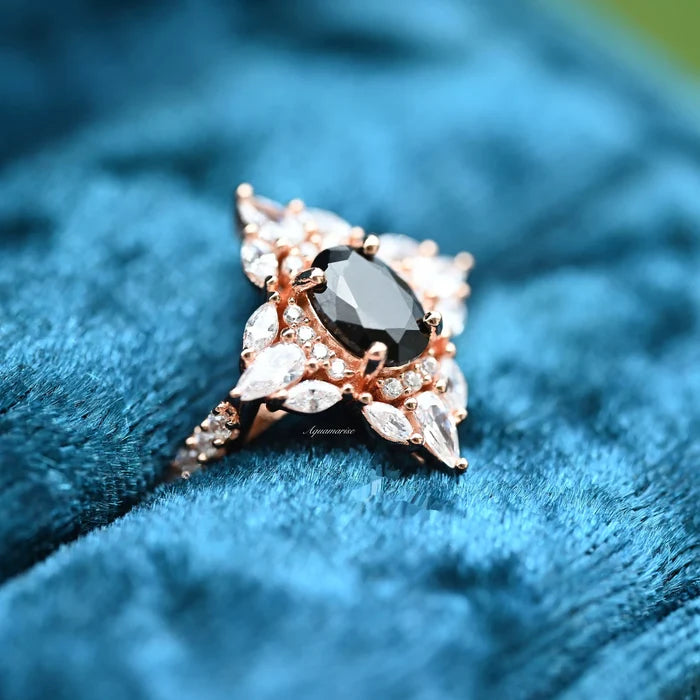 Stella Black Onyx Ring- 14K Rose Gold Vermeil by Aquamarise, featuring an oval black onyx surrounded by pear and marquise shaped stones in a vintage-inspired design on blue velvet.