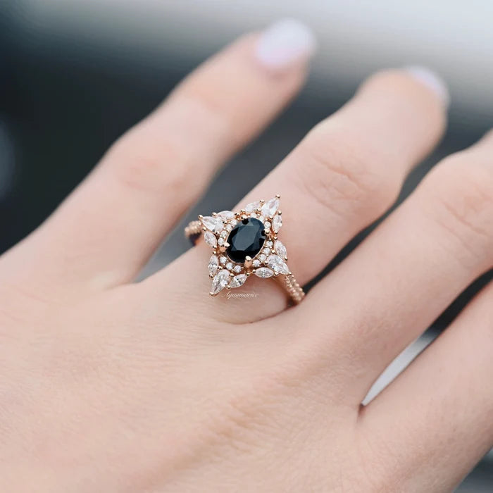 Stella Black Onyx Ring- 14K Rose Gold Vermeil by Aquamarise, featuring an oval black onyx surrounded by pear and marquise stones in a vintage-inspired star design on a finger.