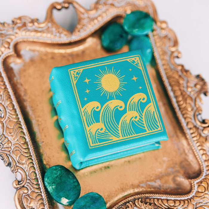 Summer Court Handmade Leather Book Ring Box- Ocean Tide Teal Edition (Small) displayed on ornate gold tray with teal stones, ideal for symbolic jewelry gifts by Aquamarise.