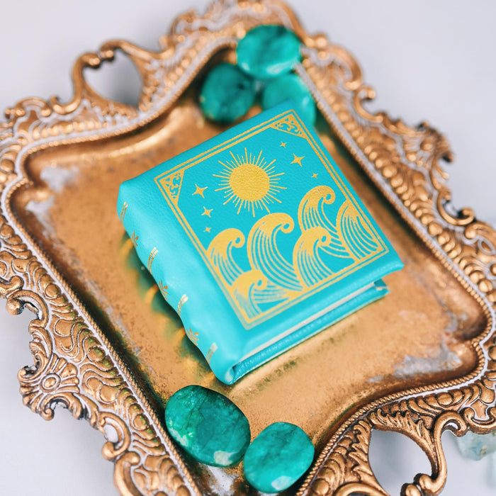 Summer Court Handmade Leather Book Ring Box- Ocean Tide Teal Edition (Small) by Aquamarise displayed on ornate gold tray with teal stones from Ring Boxes & Keepsake Proposals collection.