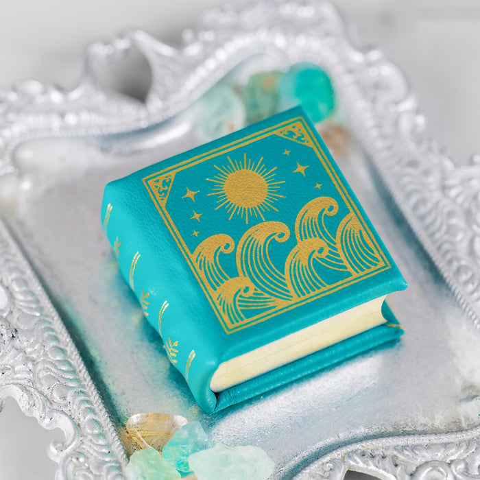 Summer Court Handmade Leather Book Ring Box- Ocean Tide Teal Edition (Small) by Aquamarise, teal leather with gold sun and waves design, displayed on ornate silver tray with crystals.