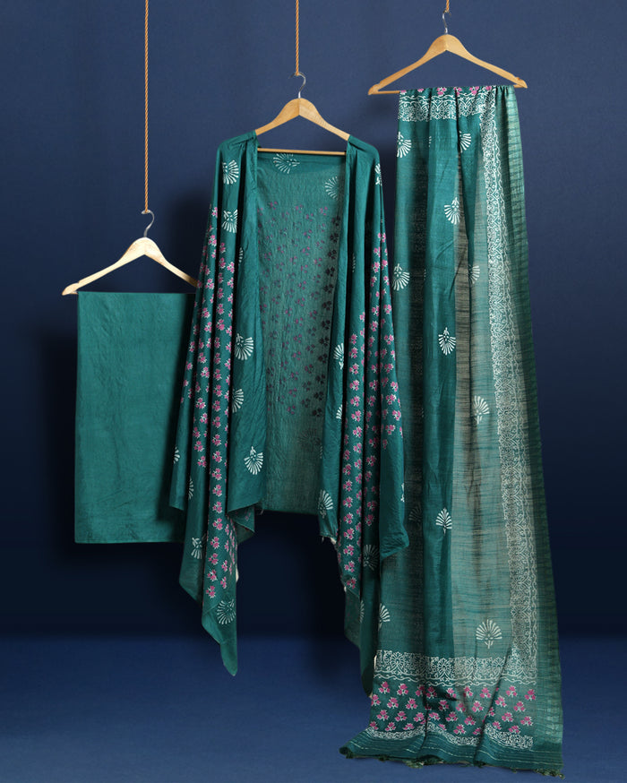 Teal green katan silk unstitched suit set with contrasting pink and white floral hand block print and a rectangular geometric frame bordering the dupatta.
