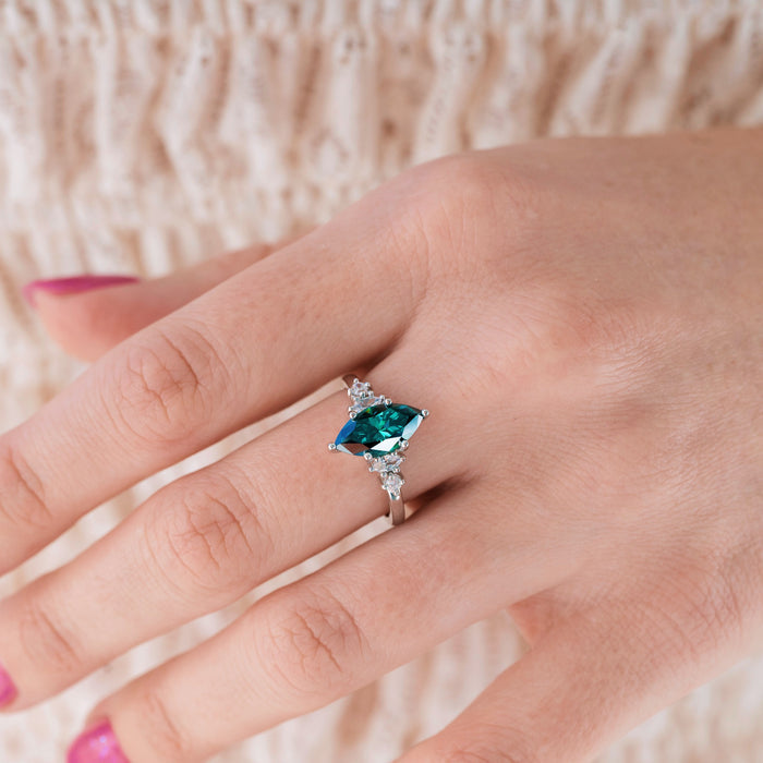 Ring with a green gemstone on a hand against a neutral background