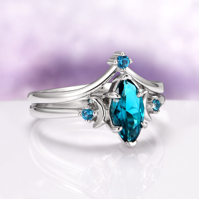 Teal Sapphire Crescent Moon Ring Set in 14K White Gold featuring a marquise-cut teal sapphire center complemented by round teal sapphires on a sleek white gold band, crafted by Aquamarise Gold from nature-inspired and fantasy engagement collections.