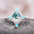 Green Moss Agate & Fire Opal Engagement Ring- 14K White Gold featuring a pear-shaped green moss agate center stone surrounded by sparkling white diamonds and accented with glowing fire opal marquise shapes, designed by Aquamarise Gold.