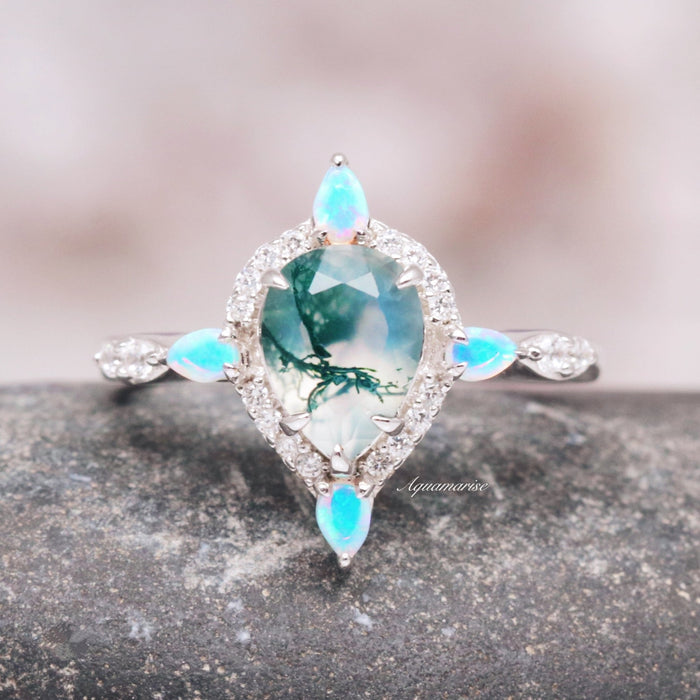Green Moss Agate & Fire Opal Engagement Ring- 14K White Gold featuring a pear-shaped green moss agate center stone surrounded by sparkling white diamonds and accented with glowing fire opal marquise shapes, designed by Aquamarise Gold.