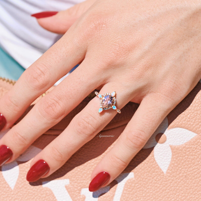 Teardrop Morganite & Fire Opal Engagement Ring in 14K Solid Rose Gold by Aquamarise Gold featuring a pear-cut morganite center with fire opal accents on an elegant hand model.