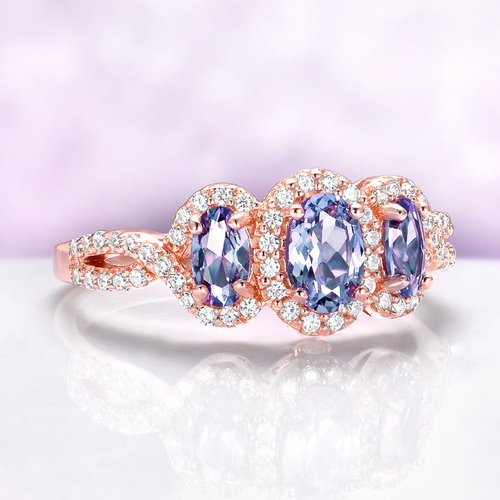 Rose gold ring with three purple gemstones on a light purple background