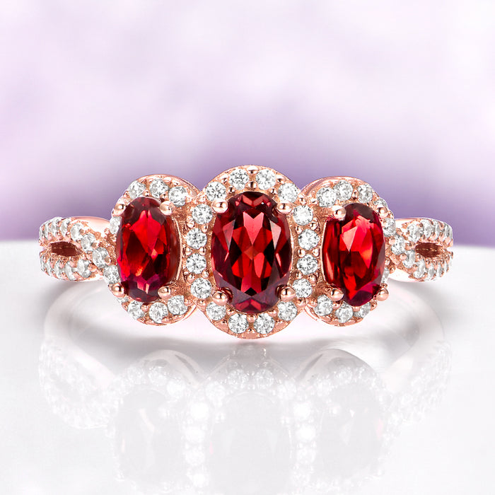 Three Stone Garnet Engagement Ring in 14K Rose Gold Vermeil by Aquamarise with three oval garnets and sparkling diamond accents in an elegant rose gold setting.
