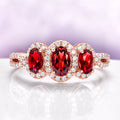 Three Stone Garnet Engagement Ring in 14K Rose Gold Vermeil by Aquamarise with three oval garnets and sparkling diamond accents in an elegant rose gold setting.