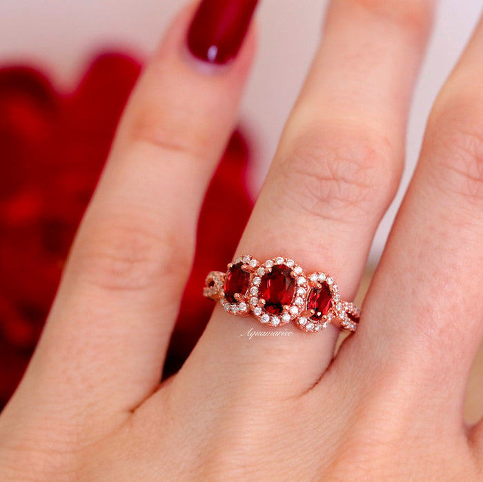 Three Stone Red Garnet Ring in 14K Rose Gold Vermeil by Aquamarise featuring three oval red garnets surrounded by sparkling accents on a twisted rose gold vermeil band.