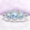 Three Stone Halo Vintage Aquamarine Engagement Ring in Sterling Silver by Aquamarise, featuring oval aquamarine stones surrounded by pavé halos on a twisted infinity silver band.