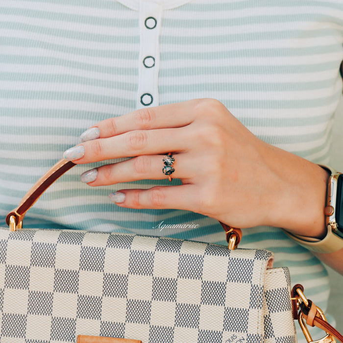 Toi Et Moi Moss Agate Ring in Solid 14K Rose Gold by Aquamarise Gold, featuring two natural moss agate stones, shown on a hand holding a checkered designer handbag.