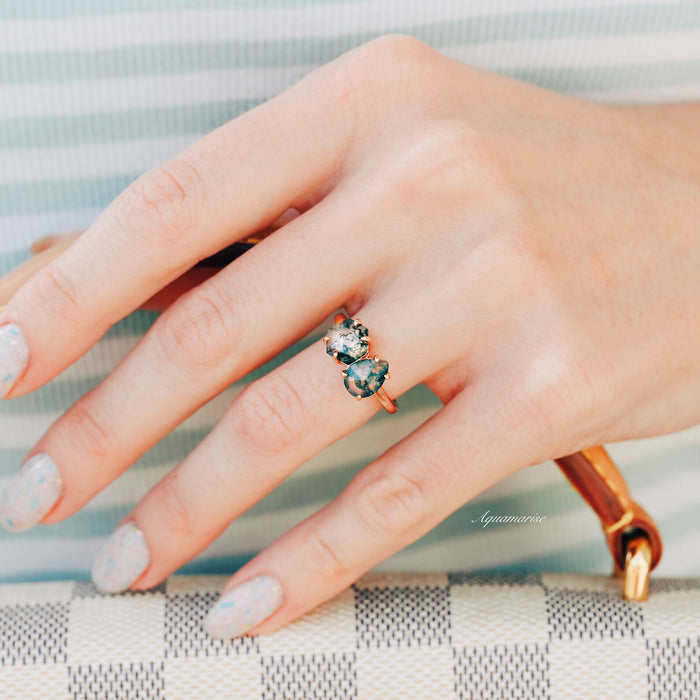 Toi Et Moi Moss Agate Ring in Solid 14K Rose Gold by Aquamarise Gold, featuring two natural moss agate stones, shown on a hand holding a checkered bag with pastel nail polish.