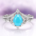 Turquoise Opalescent Blue Sapphire Ring Set in Sterling Silver by Aquamarise, showcasing a pear-shaped vibrant turquoise blue sapphire set in 925 sterling silver with intricate leaf-inspired detailing and small sparkling white gemstones.