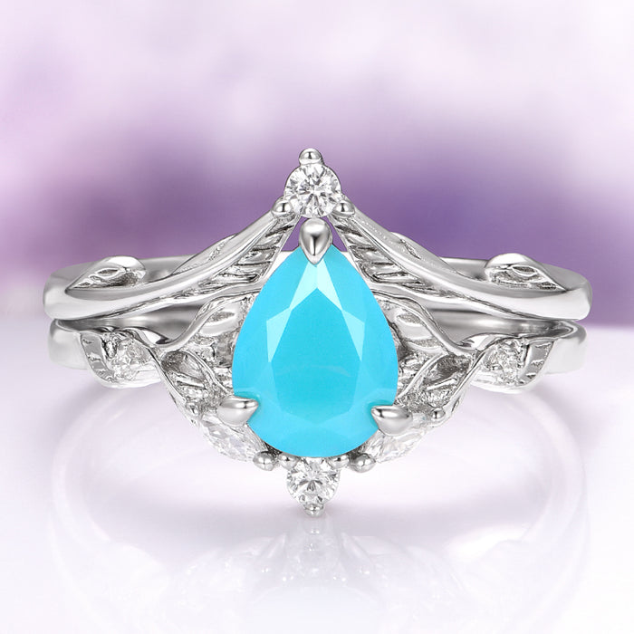 Turquoise Opalescent Blue Sapphire Ring Set in Sterling Silver by Aquamarise, showcasing a pear-shaped vibrant turquoise blue sapphire set in 925 sterling silver with intricate leaf-inspired detailing and small sparkling white gemstones.