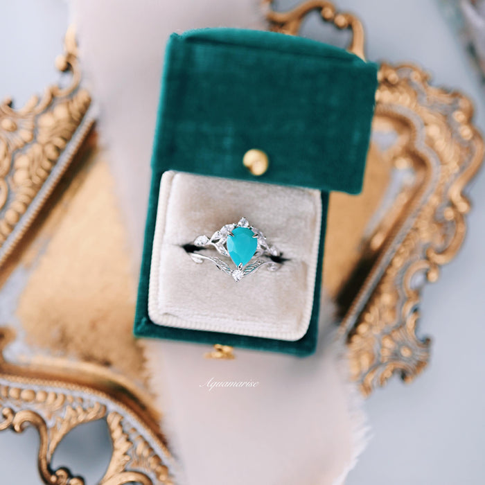 Turquoise Opalescent Blue Sapphire Ring Set in Sterling Silver by Aquamarise, featuring a pear-shaped turquoise blue sapphire set in a delicate 925 sterling silver band with intricate nature-inspired detailing, presented in a green velvet ring box.