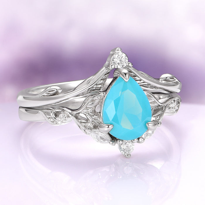 Turquoise Opalescent Blue Sapphire Ring Set in Sterling Silver by Aquamarise, featuring a pear-shaped vibrant turquoise blue sapphire centerpiece set in intricately detailed 925 sterling silver with delicate leaf-inspired accents and small sparkling white gemstones, part of collections including Sterling Silver Rings, September Birthstone Jewelry, and Nature-Inspired Engagement Rings.