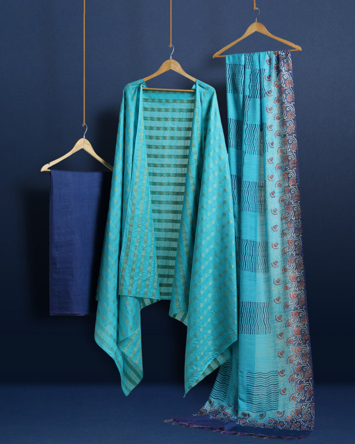 Unstitched turquoise Katan silk suit set with banded geometric stripes on the top and dense paisley-like floral block print on the dupatta, finished with a decorative border strip and fringed ends.