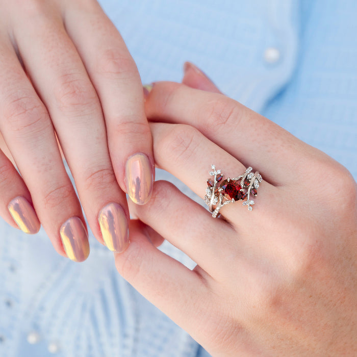Fireworks Cut Natural Red Garnet Leaf Engagement Ring in 14K White Gold by Aquamarise Gold featuring an oval fiery red garnet centerpiece embraced by intricate white gold leaf and vine details, part of Solid Gold Engagement Rings and Nature-Inspired Jewelry collections.