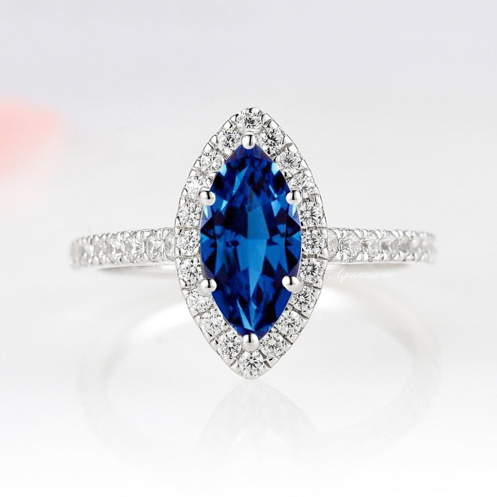 Valeria Marquise Halo Blue Sapphire Ring- Sterling Silver by Aquamarise, featuring a marquise royal blue sapphire surrounded by a halo of sparkling stones on a sterling silver band.