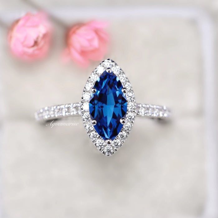 Valeria Marquise Halo Blue Sapphire Ring- Sterling Silver by Aquamarise, featuring a marquise royal blue sapphire center stone encircled by a sparkling halo on a sterling silver band.