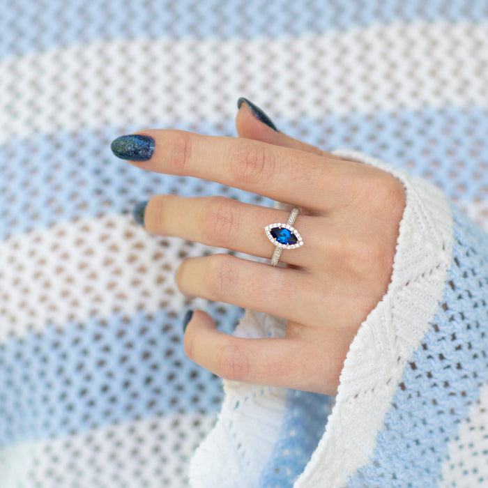 Valeria Marquise Halo Blue Sapphire Ring- Sterling Silver by Aquamarise, featuring a marquise royal blue sapphire center stone framed by a halo of sparkling stones on a sterling silver band.