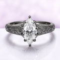 Victorian Gothic Moissanite Filigree Engagement Ring in Black Ruthenium featuring a marquise cut stone on a black ruthenium-finished sterling silver band with intricate Victorian scrollwork by Aquamarise Gold.