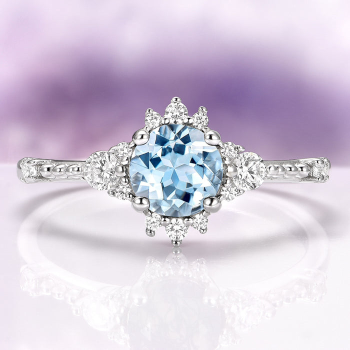 Vintage Round Cut Aquamarine Ring in Sterling Silver by Aquamarise featuring a delicate round aquamarine center with intricate vintage-inspired diamond accents on a detailed silver band.