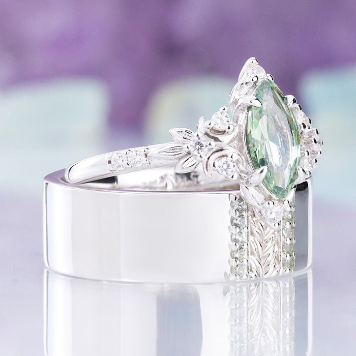 Angled view of the Viridian green tourmaline men's band with the matching women's ring resting on it, sold together as a couples set