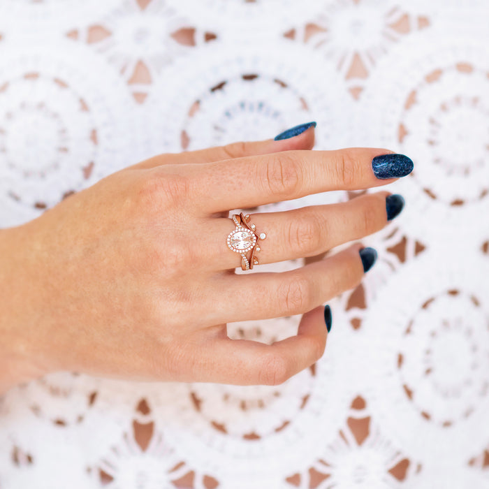 Hand wearing Lab-Grown Diamond Leaf Engagement Ring Set in 14K Solid Rose Gold (IGI Certified) with blue nail polish, displayed over white lace background.