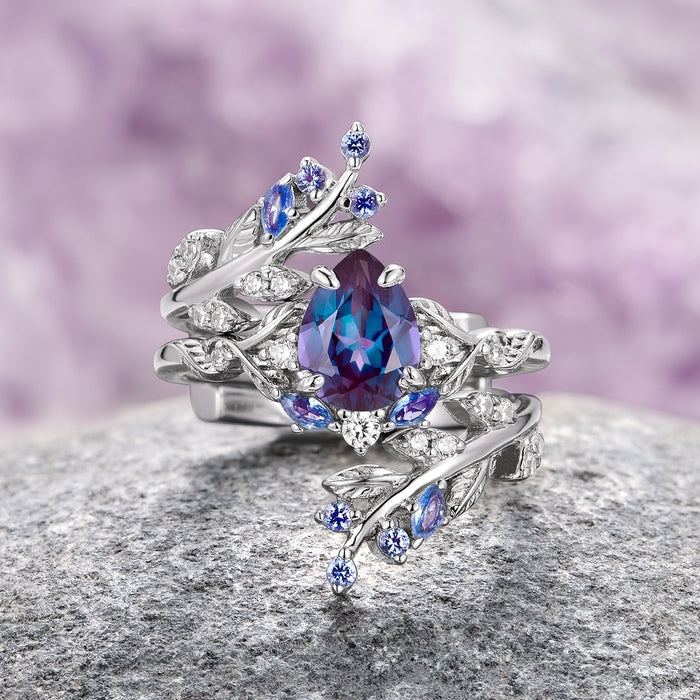 Wisteria Alexandrite Leaf Couples Ring Set by Aquamarise featuring a pear-shaped lab-grown alexandrite center with leaf-inspired sterling silver bands accented with small blue and clear gemstones, part of Matching Couples' Rings and June Birthstone Jewelry collections.