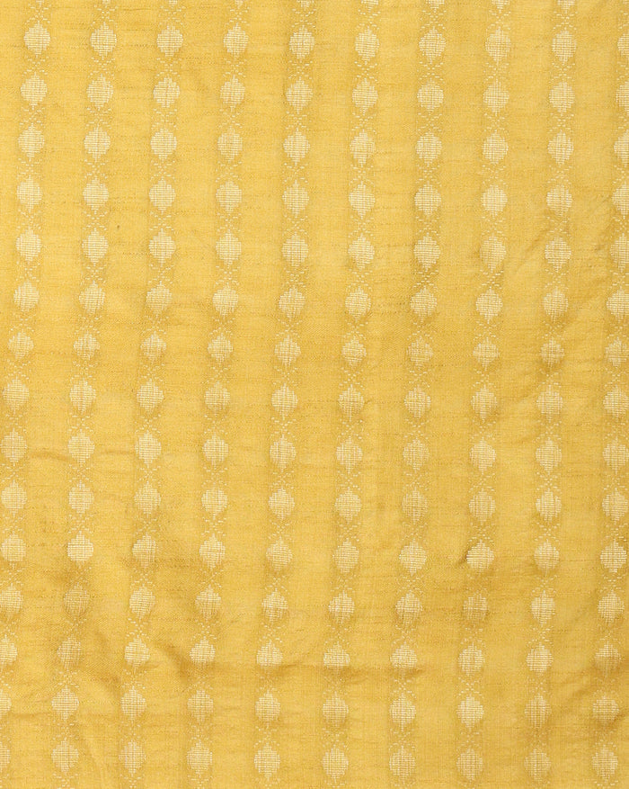 Unstitched yellow Katan silk three piece with small grey ovoid block printed motifs, a densely printed bottom, a sparsely printed top and a dupatta with a floral bordered panel and frayed fringe ends.